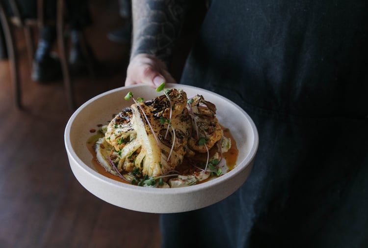 Waiter at Cucina holding a cauliflower dish.