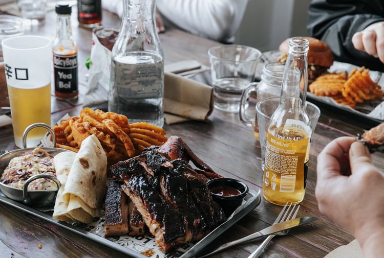 A plate of meat and chips on a table sittling alongside beers.
