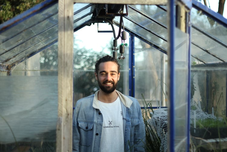 Jayden Kilnac looking to camera outside a glass house.