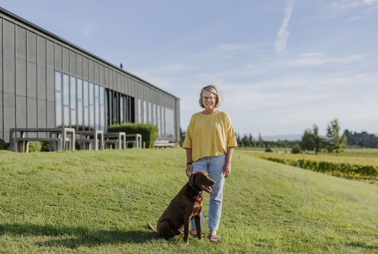 Pen and her dog standing in front of Black Estate on a sunny day.