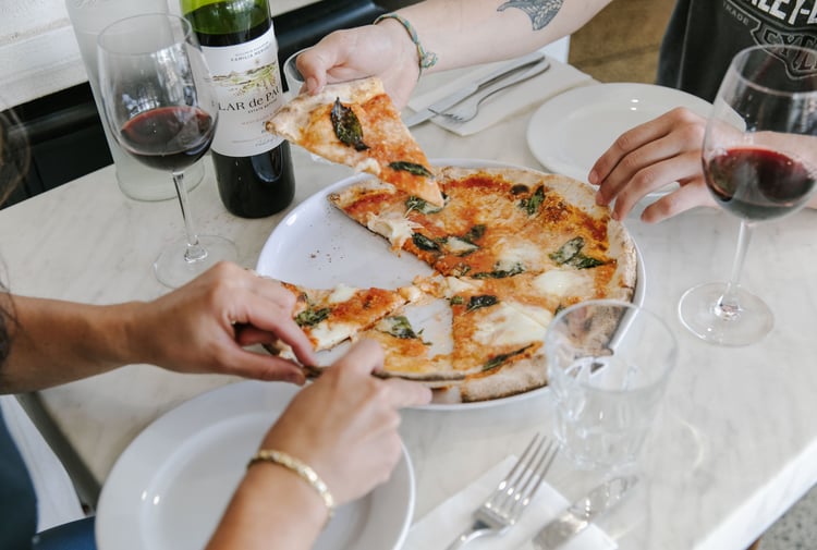 Diners enjoy a slice of pizza from one of the 10 best pizza spots in Christchurch.