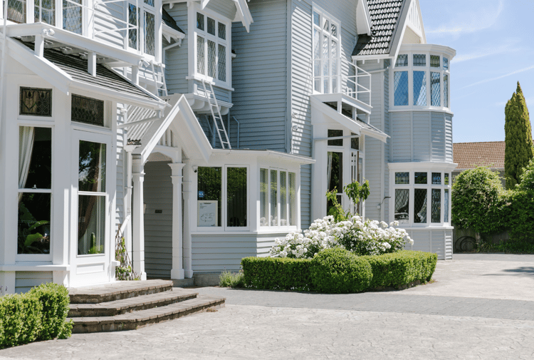 The exterior of Christchurch accommodation with roses and hedged in front.