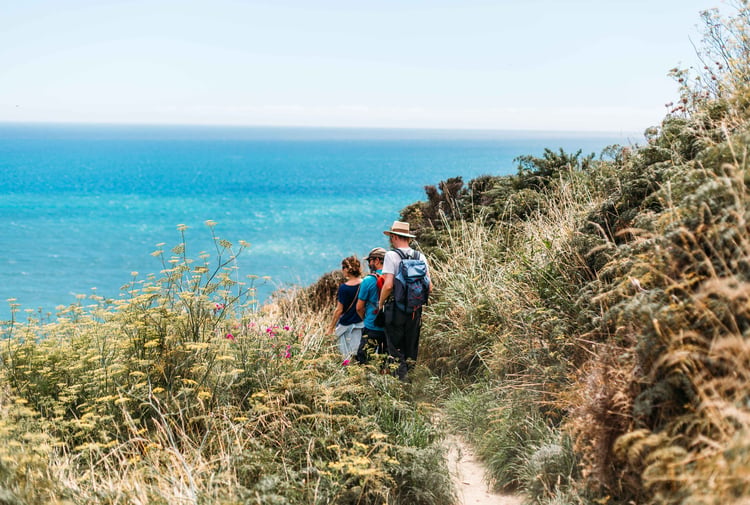A group of people are walking on a track with the ocean in the background.