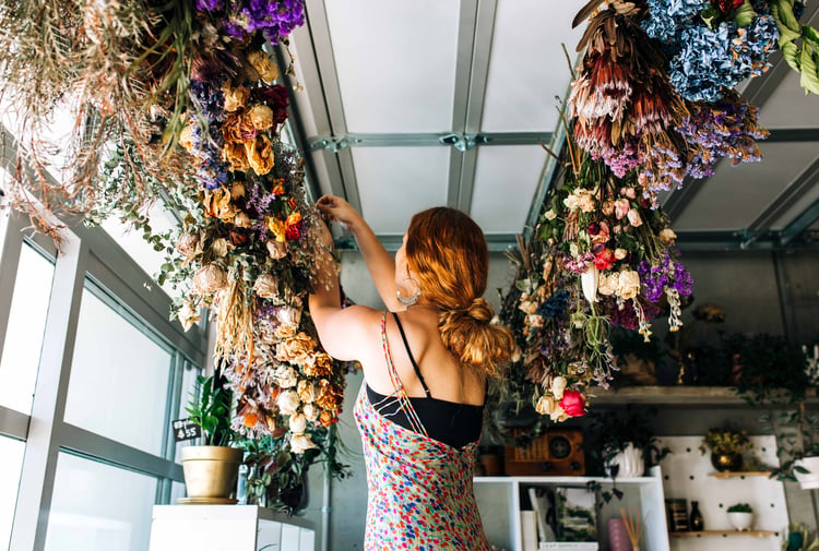 A woman working on bouquets hanging from the ceiling.