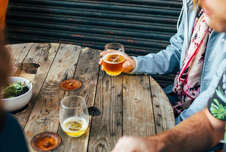 A hand holding a glass of beer inside Bootleg Brewery.
