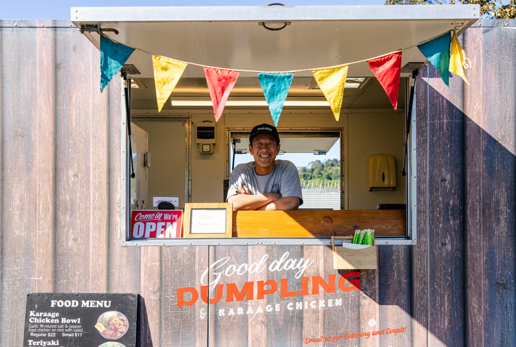Food truck in a carpark with the road in the background.