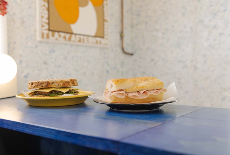 Two simple sandwiches placed next to each other on blue table at Odds in Christchurch