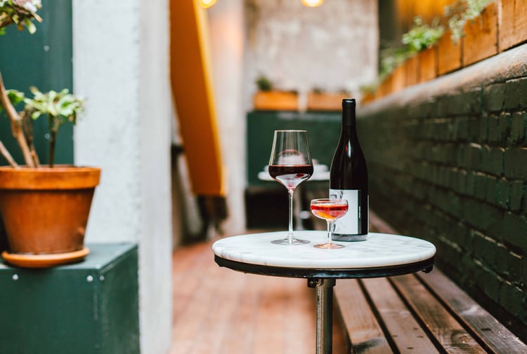 Glasses and a bottle of wine sitting on a table in the outdoor seating area of Puffin Wine Bar in Wellington.