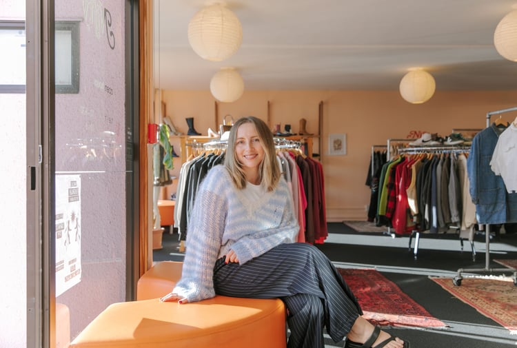 Photo of Rosie Carroll sitting on orange semi-circle couch at her secondshop Nifty in Christchurch