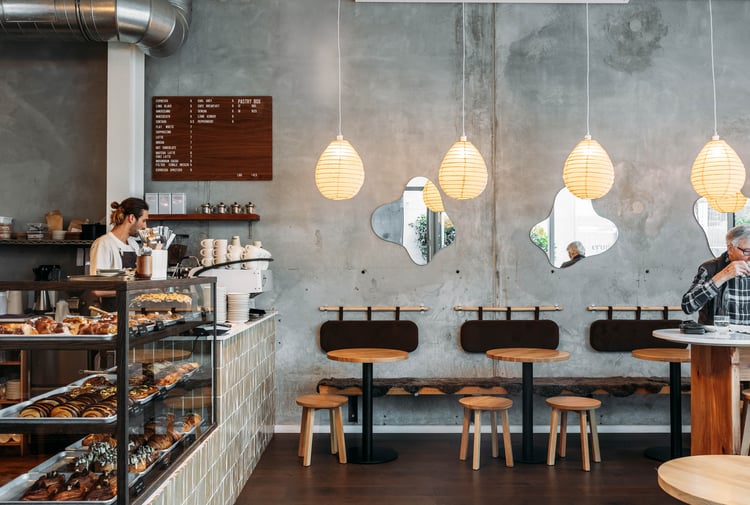 Barista behind counter and customer sitting at table at Crumb Bakehouse.