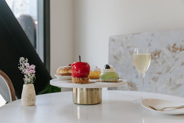 Shiny cakes on a cake stand on a white table.