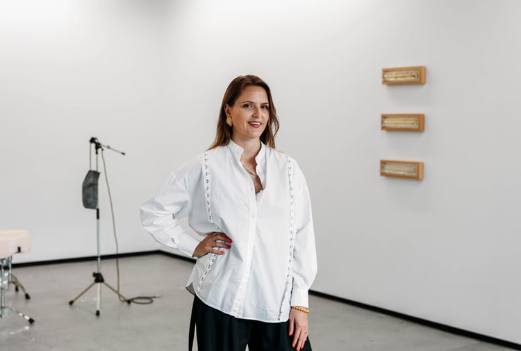 A woman with her hand on her hip in front of a gallery space.