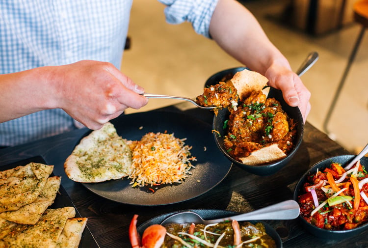 Indian food being scooped onto a plate.