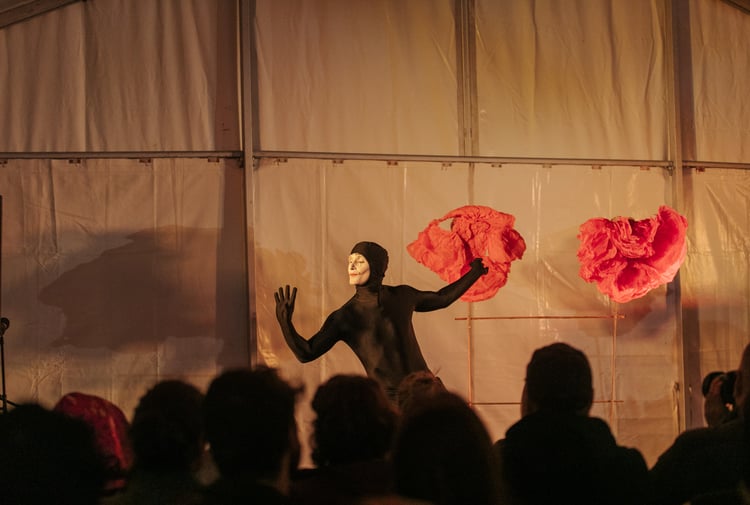 A man dressed in a black holding a red piece of fabric.