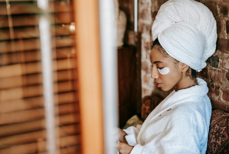 Women in spa with under-eye skincare patches wearing a dressing gown and towel wrapped around head