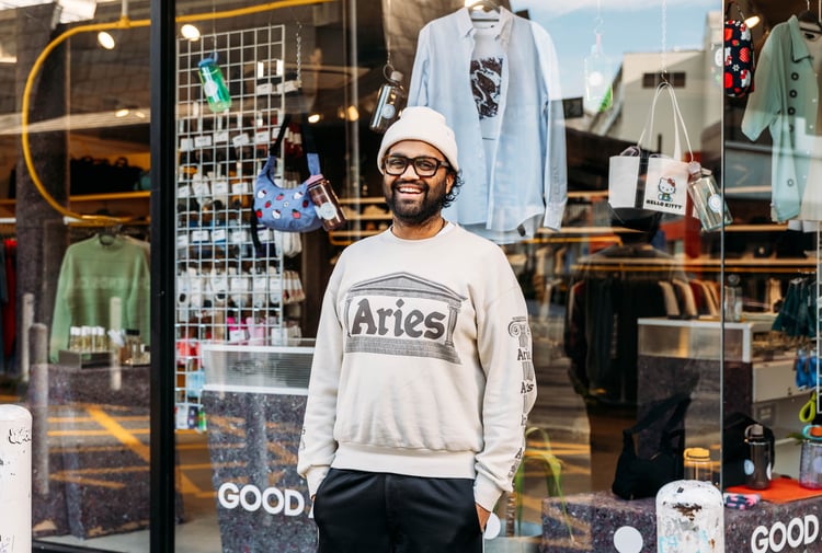 A man wearing a casual clothes smiling to camera outside a shop in Wellington.