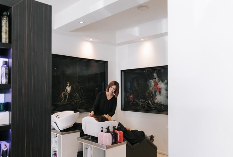 Hairstylist washing a woman's hair at Mod's Hair in Christchurch.