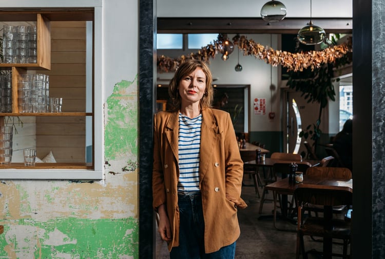 A woman in her cafe posing for the camera.