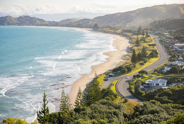 Road runs alongside the coastline, the waves on the beach meet the sand.