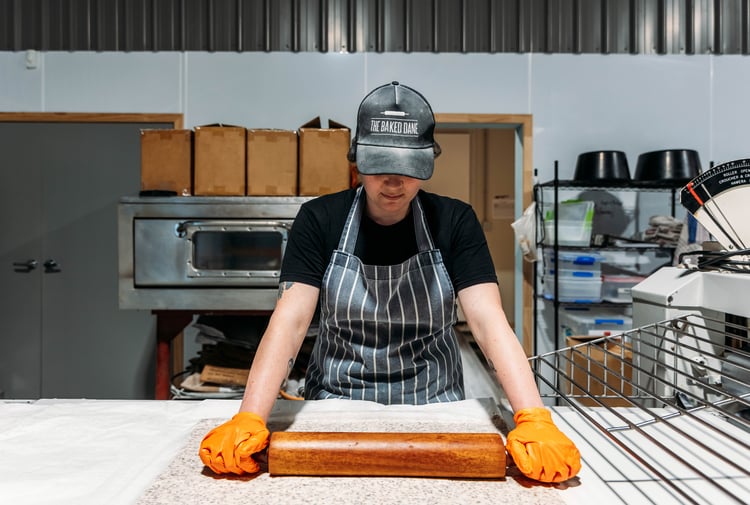 Baker rolling out dough in the kitchen at The Baked Dane.