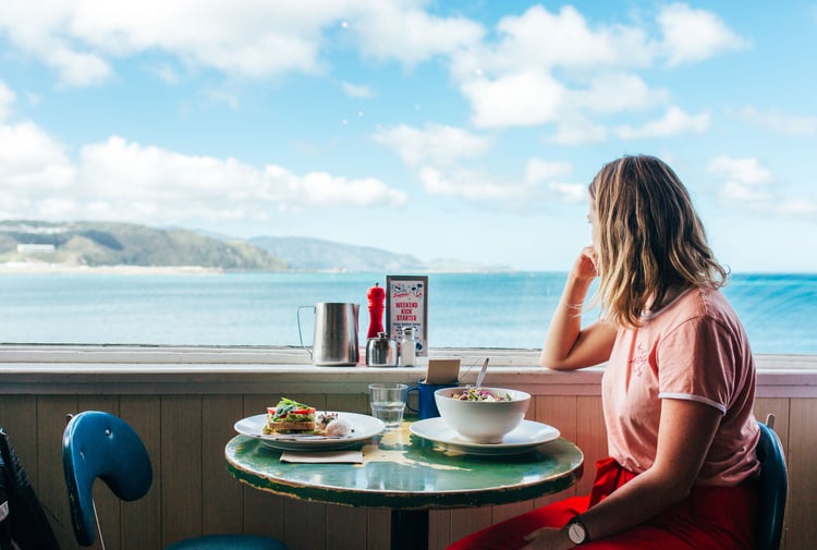 A woman looking out towards the ocean on a sunny day.