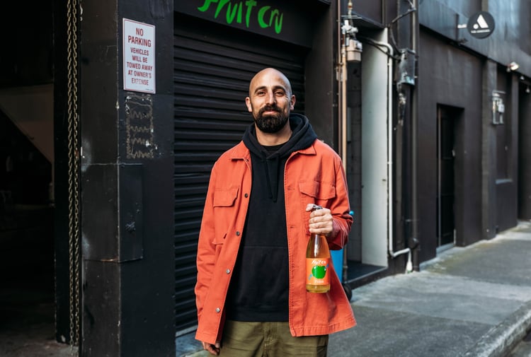 Cosmo holding a bottle of Fruit Cru.