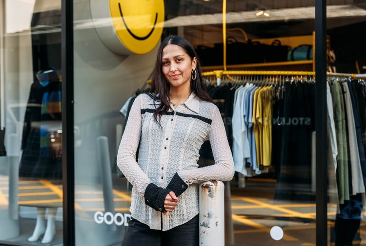 A woman wearing black and white standing in front of a clothing store.