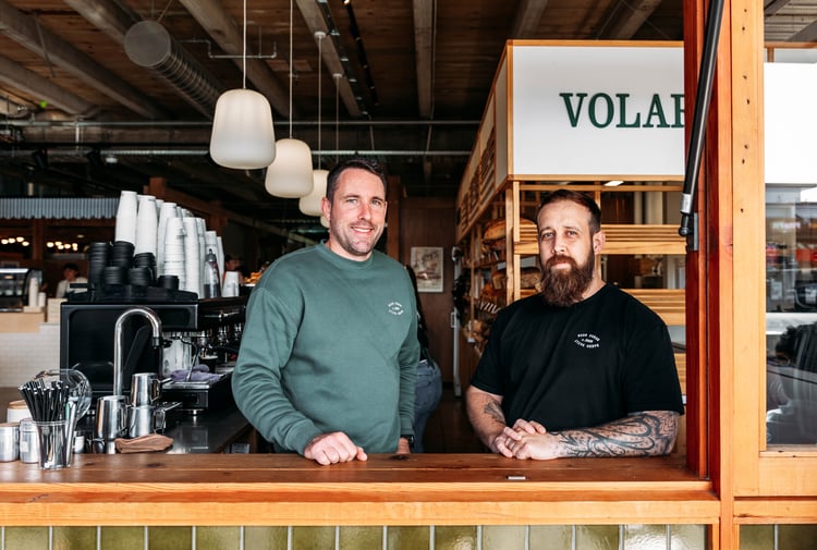 Two men smiling to camera.