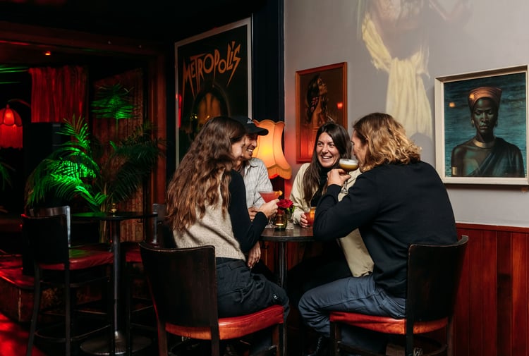 People sitting around in a dimly lit room drinking.