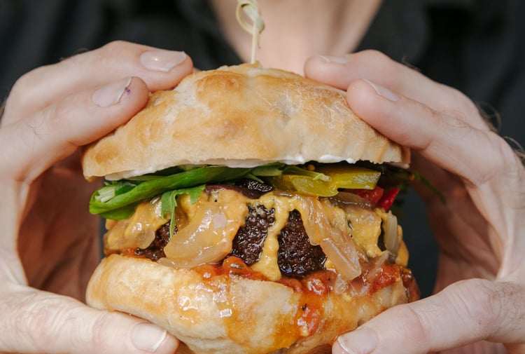 Close up of hands holding a vegan burger.