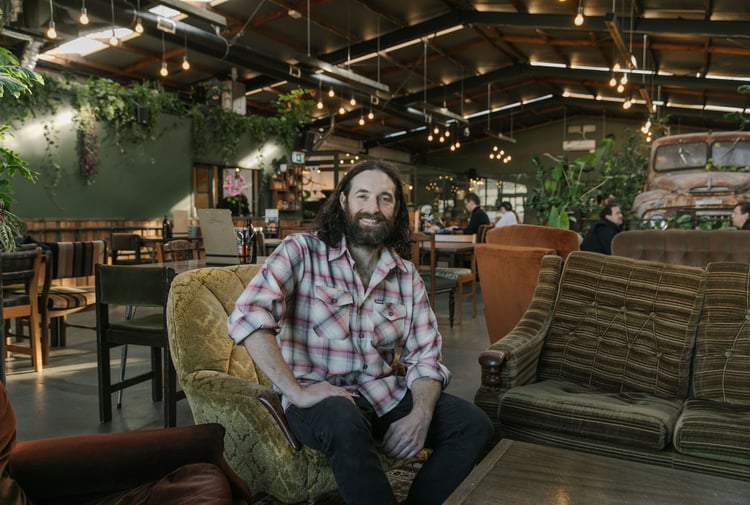 Chef Pedro Johnston sitting on couch smiling at Scoundrel in Christchurch