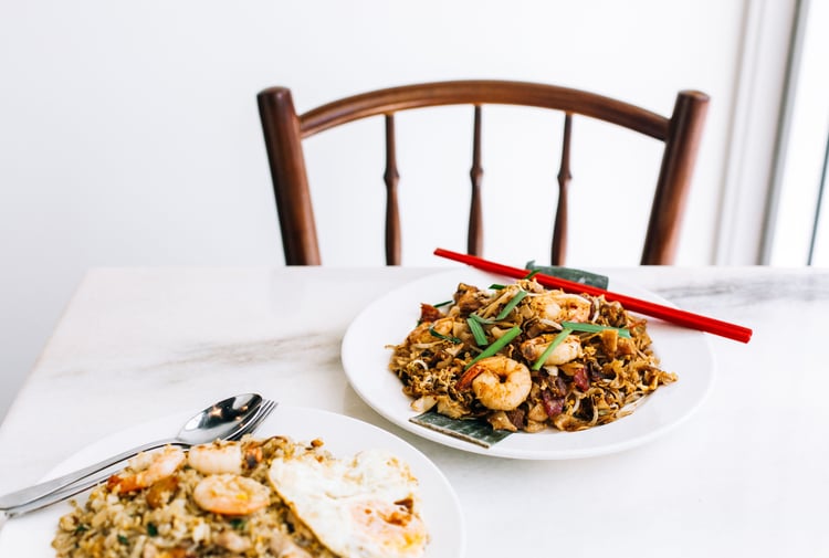 A bowl of noodles and a bowl of fried rice against a white background.