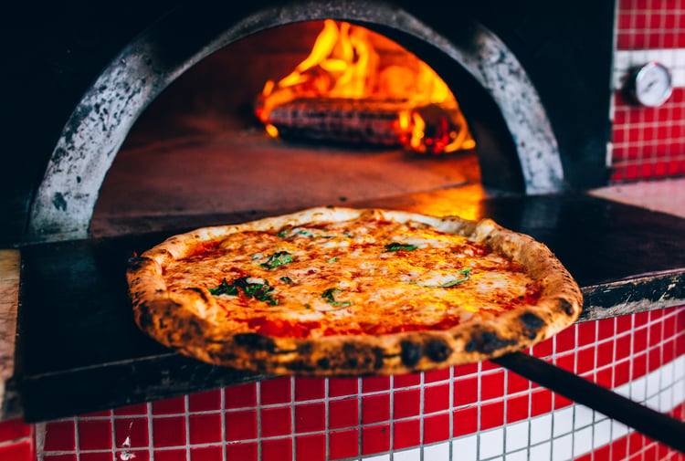 A pizza coming out of a hot oven.