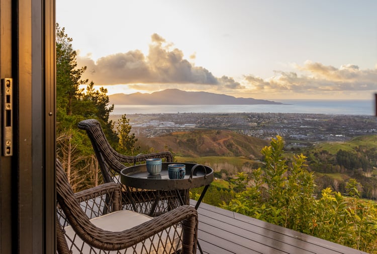 Table and chairs on a balcony overlooking the coastline.