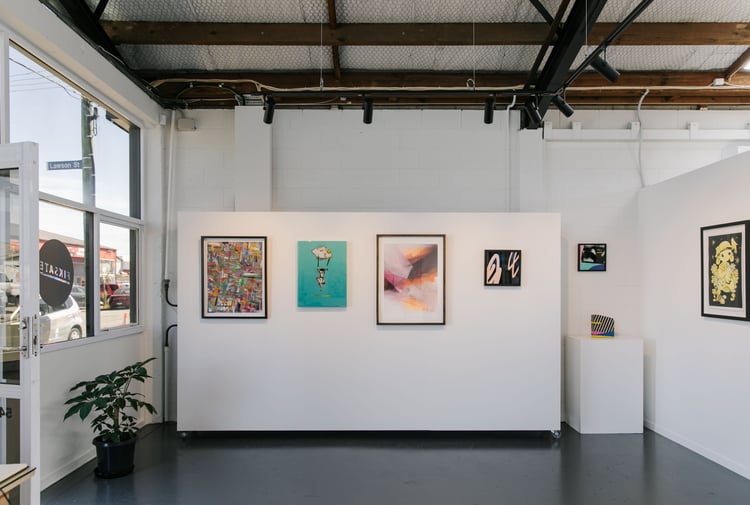 Open celling gallery with wooden beams and walls covered in bright artwork.