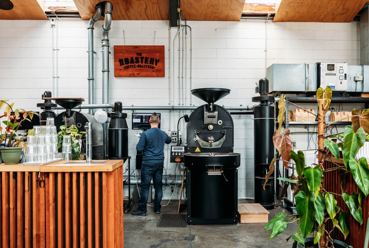 Man standing at coffee bean roaster.