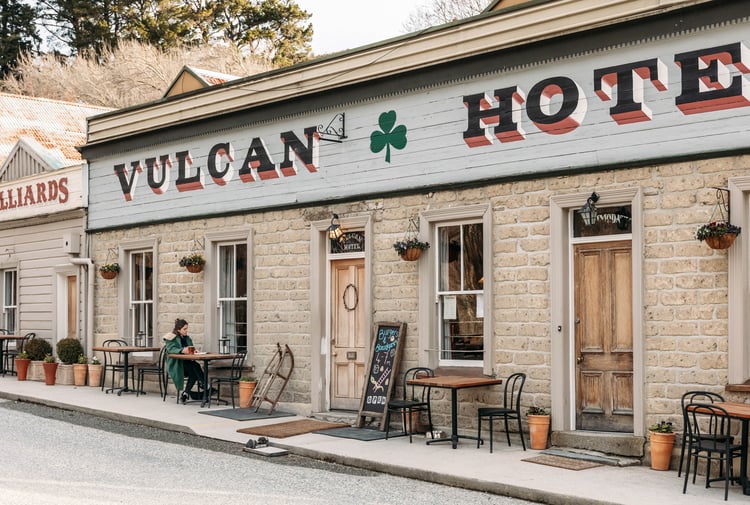 A woman sitting at a table outside Vulcan Hotel in Central Otago.
