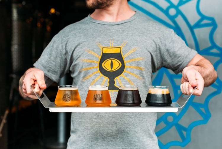 A man holding a tasting tray of beers.