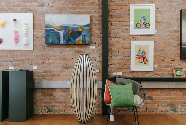 Interior view of art hanging on a brick wall at 77 Art + Living.