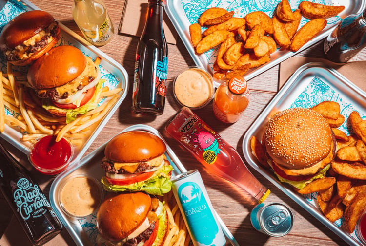 Birds eye view of silver trays filled with burgers and fries.