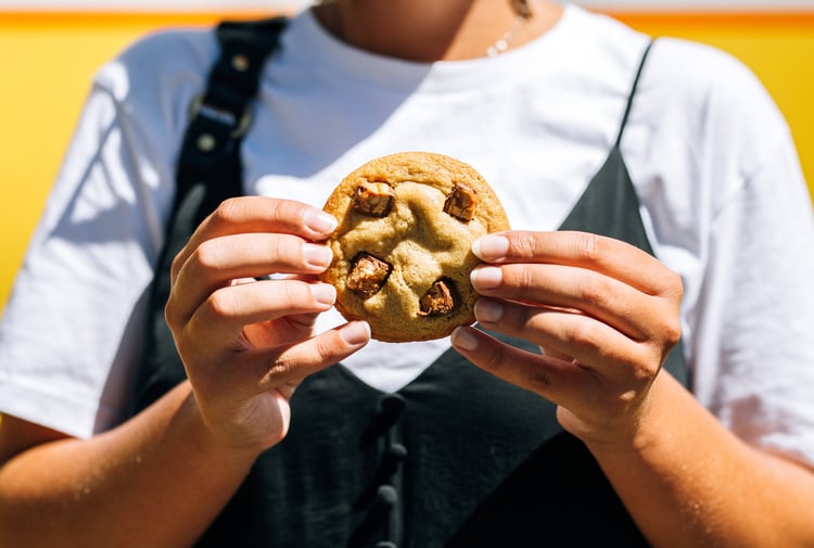 A woman holding a cookie in two hands.
