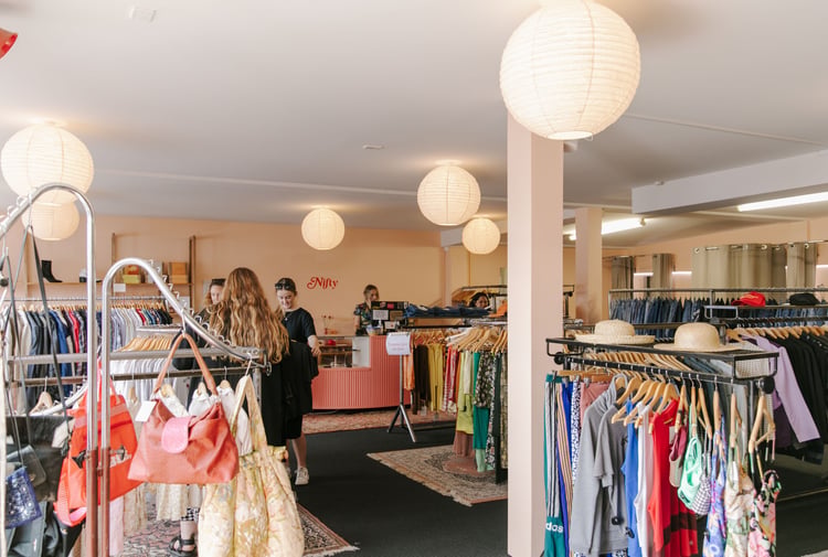 The busy and bright interior of a second hand clothing store.