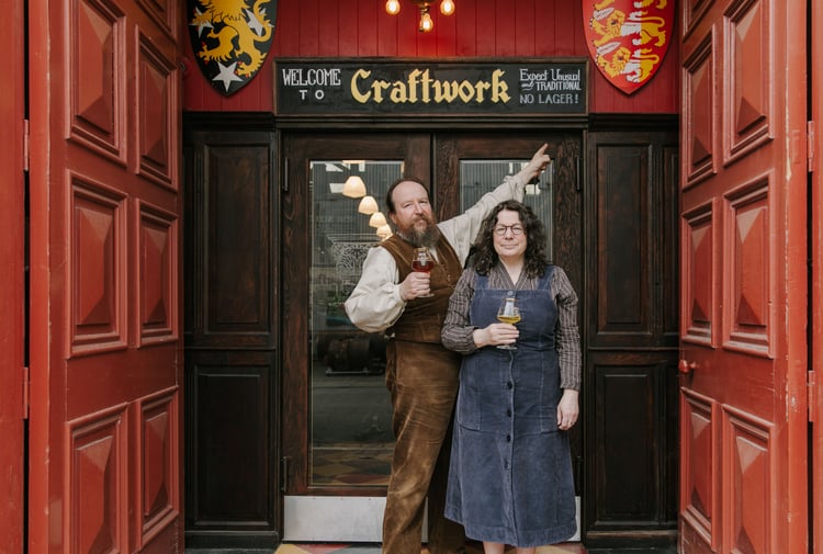Owners of Craftwork standing outside the building with a pint in hand.