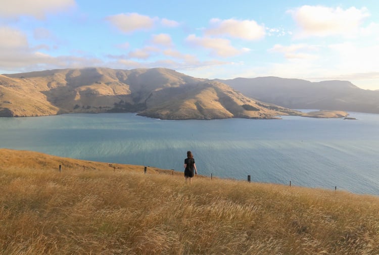 A woman walking on a hill with the ocean in the background.