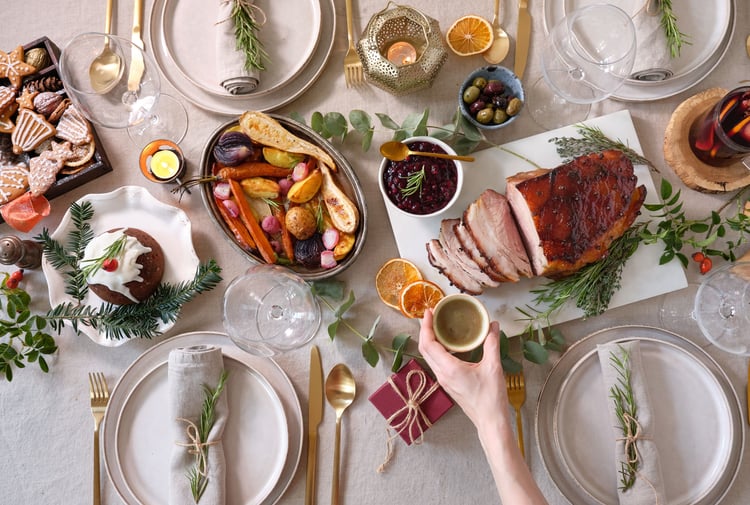 A hand holding a glass of champagne over a Christmas table setting.