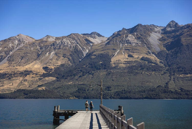 People standing on a wharf at a lake on a sunny day.