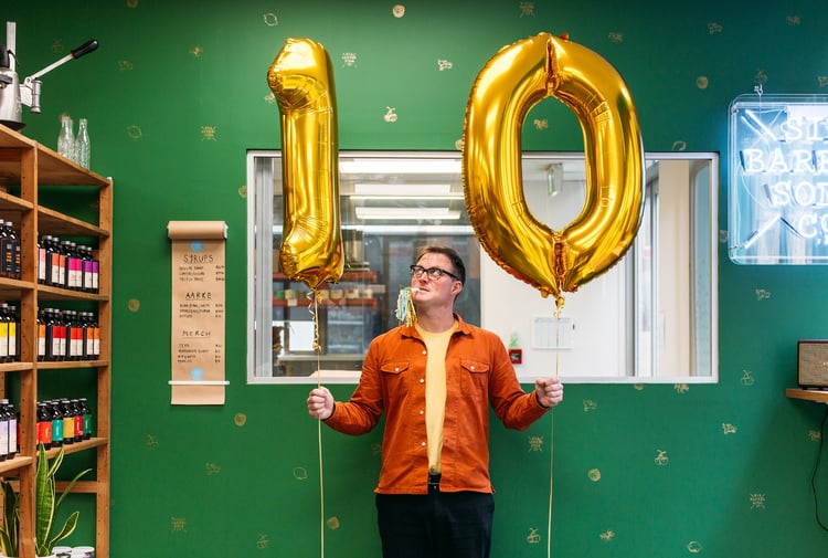 Joe Slatter holding two gold ballons with the numbers 1-0.