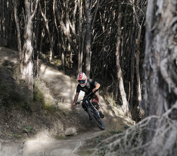 Man riding downhill through forest at Middle Hill MTB.