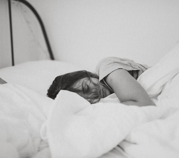 Woman lying in bed by Kinga Cichewicz.