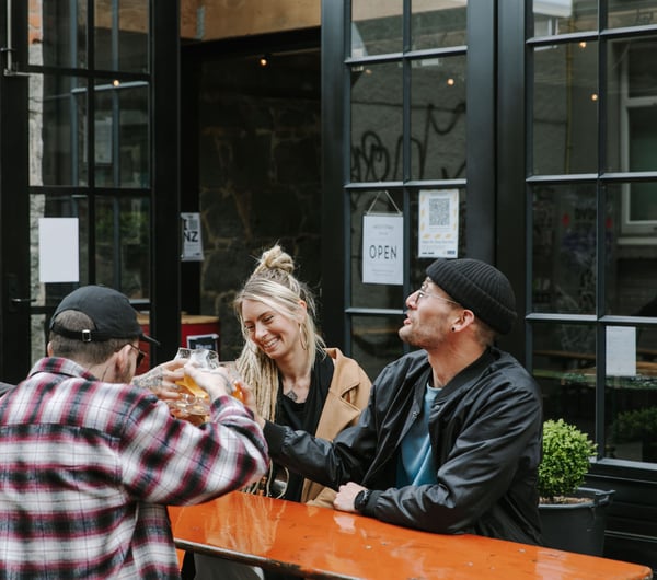 A group of people sat around a table drinking beer at Steamer Basin, Dunedin.